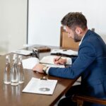 Business owner and entrepreneur signing corporate legal paperwork for EU Blue Card and German residence permit in a modern office