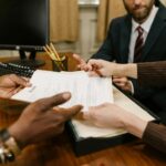 Professional business meeting in Germany: entrepreneurs signing legal documents for company ownership and business visa in modern office, supporting legal residence for international business people and families.